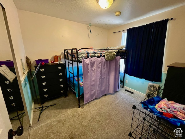 Bedroom with a textured ceiling and carpet