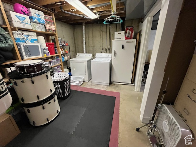 Basement featuring washing machine and clothes dryer and white refrigerator