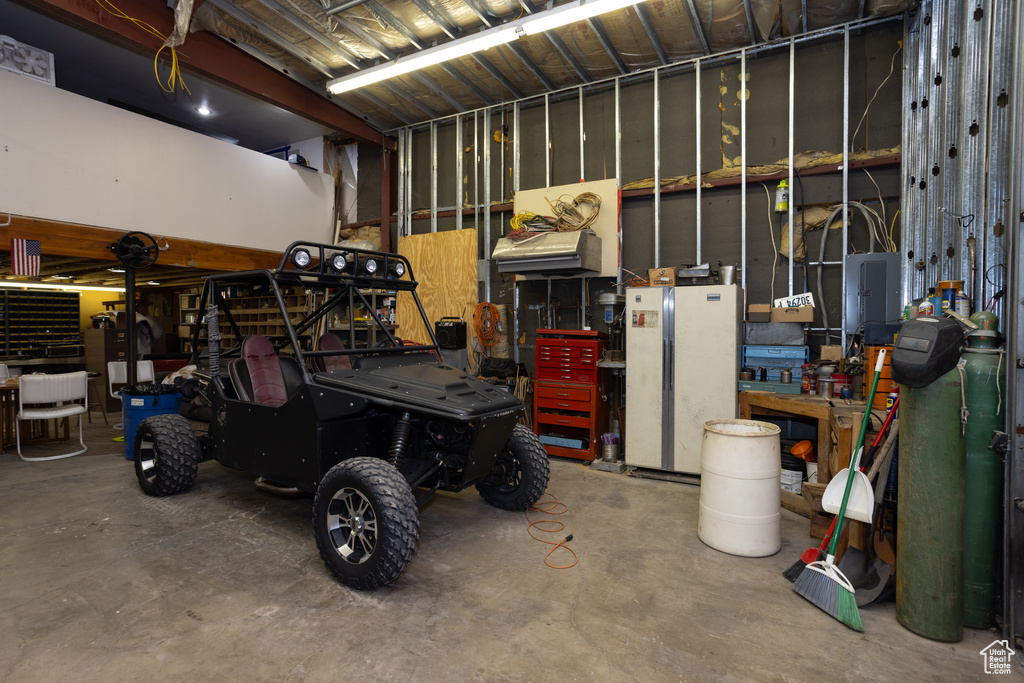 Garage with a workshop area and white refrigerator