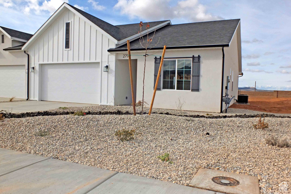 View of front of home featuring central AC unit and a garage