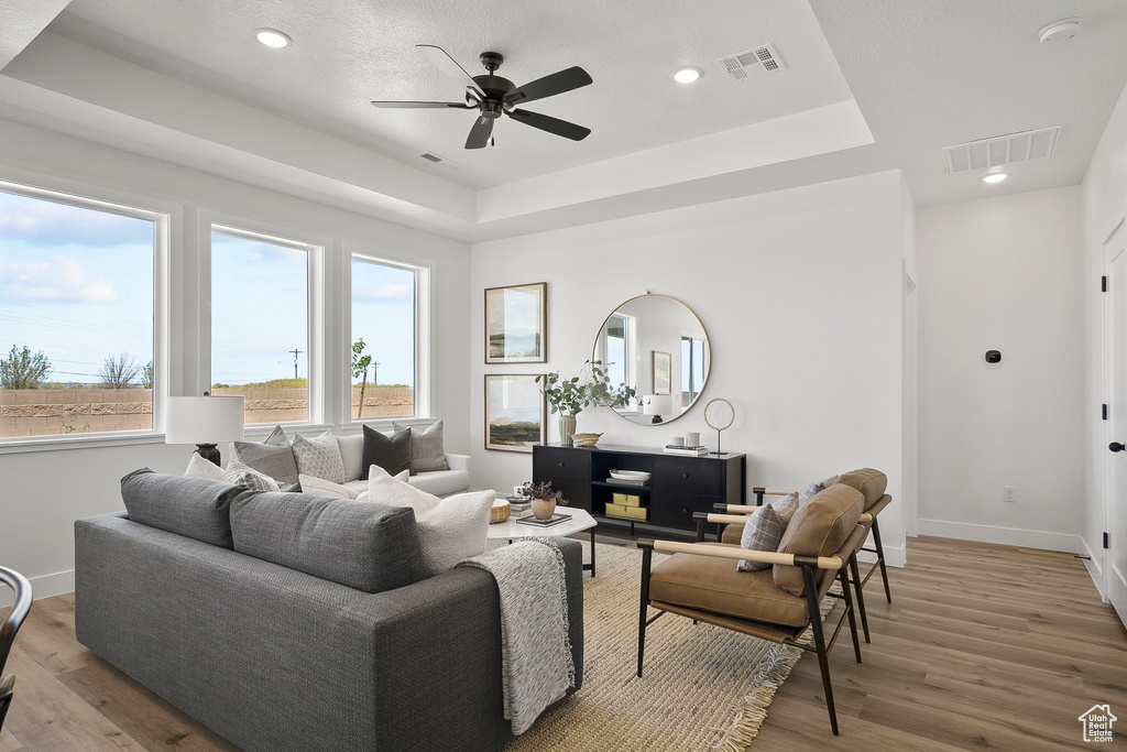 Living room with a tray ceiling, hardwood / wood-style flooring, and ceiling fan