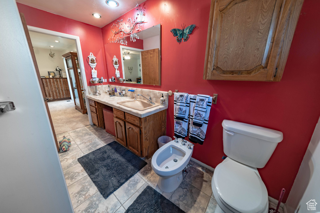 Bathroom with tile floors, a bidet, vanity, and toilet