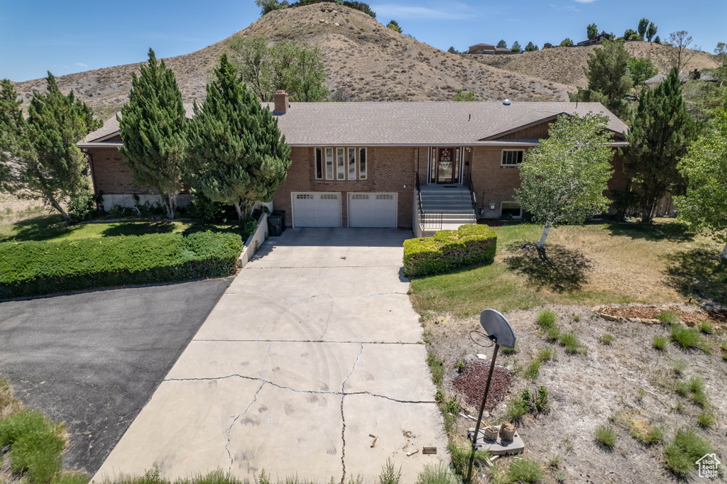 Single story home featuring a garage, a mountain view, and a front lawn