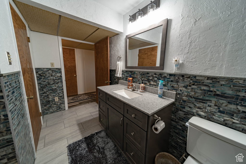 Bathroom featuring tile walls, tasteful backsplash, oversized vanity, and toilet