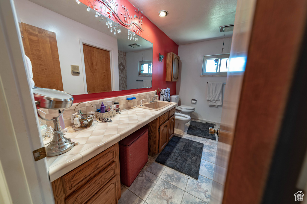 Bathroom with tile flooring, a bidet, backsplash, vanity, and toilet