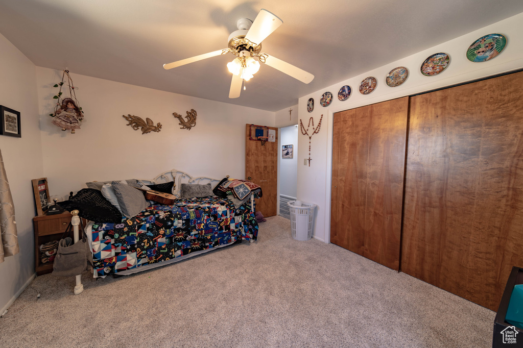 Carpeted bedroom featuring a closet and ceiling fan