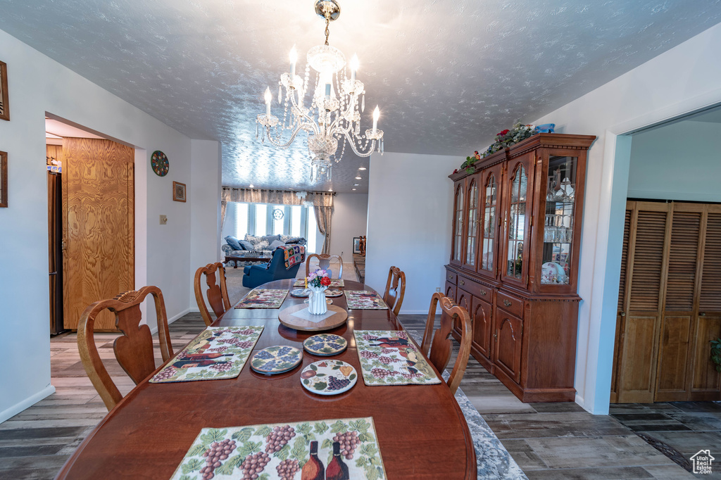 Dining space with hardwood / wood-style floors, a chandelier, and a textured ceiling