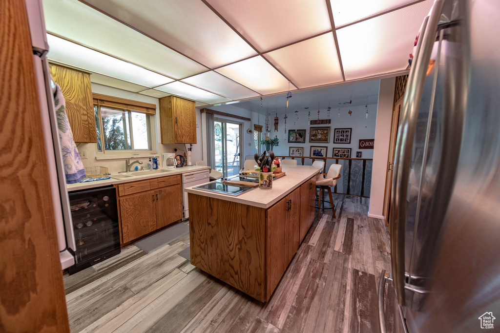 Kitchen with a center island, hardwood / wood-style flooring, stainless steel refrigerator, wine cooler, and sink