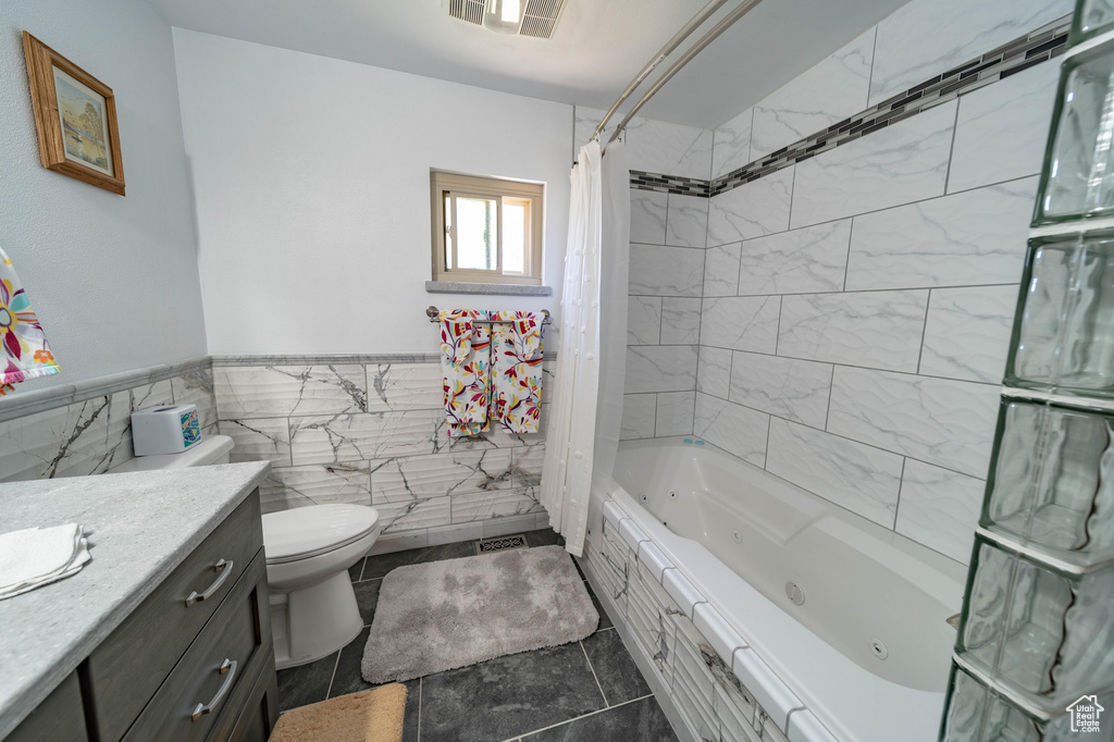 Full bathroom featuring tile floors, shower / tub combo, toilet, and tile walls