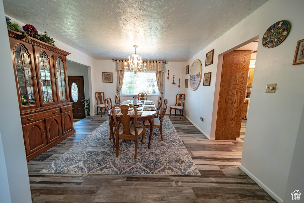 Dining room with a chandelier, a textured ceiling, and dark hardwood / wood-style floors