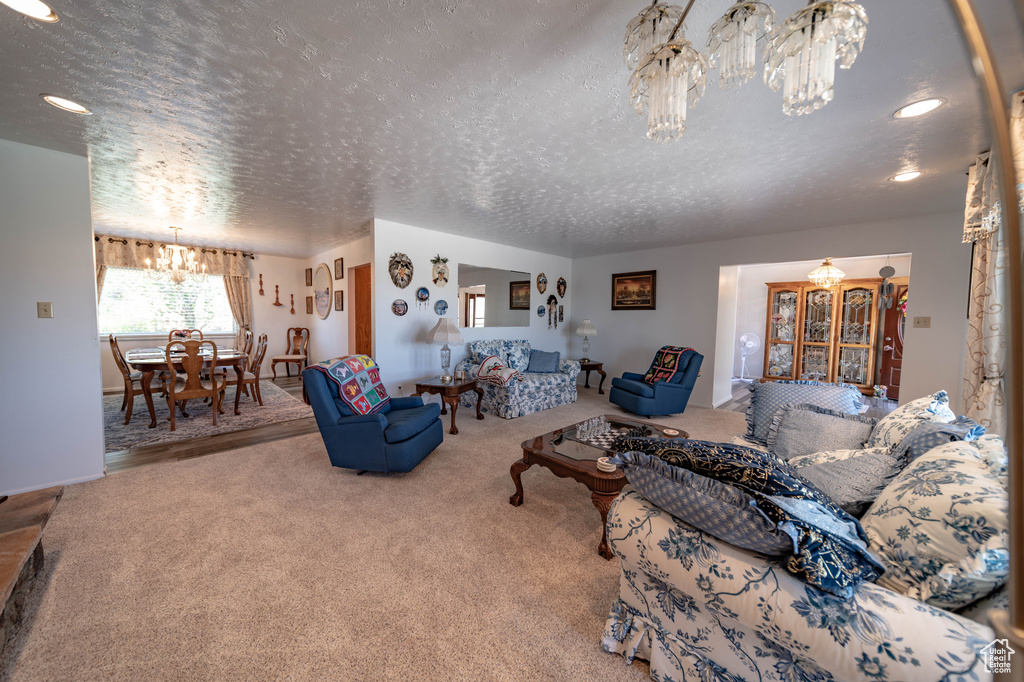 Living room featuring carpet flooring, a notable chandelier, and a textured ceiling