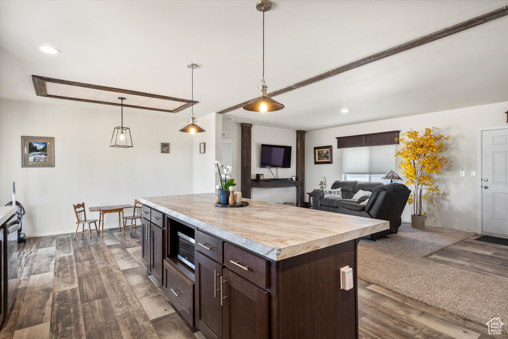 Kitchen featuring decorative light fixtures, dark brown cabinetry, dark hardwood / wood-style flooring, a kitchen island, and butcher block countertops