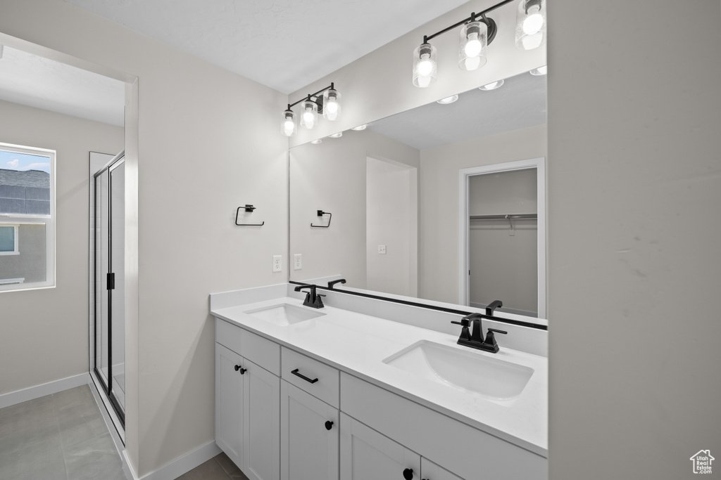 Bathroom with an enclosed shower, tile patterned floors, and vanity