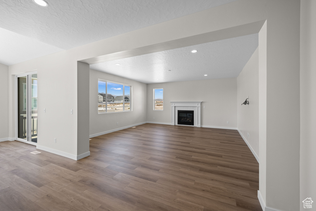 Unfurnished living room featuring hardwood / wood-style flooring and a textured ceiling