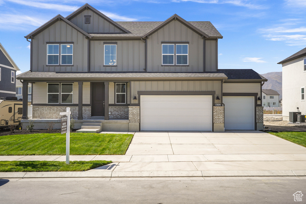 Craftsman-style home with central AC unit, a garage, a front yard, and covered porch