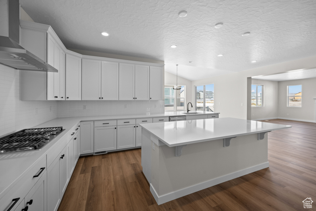 Kitchen with wall chimney exhaust hood, decorative backsplash, dark hardwood / wood-style flooring, and white cabinetry