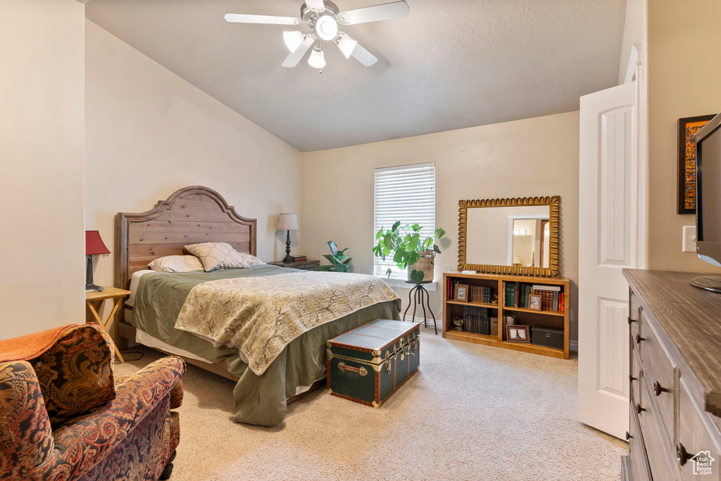 Carpeted bedroom with ceiling fan and vaulted ceiling