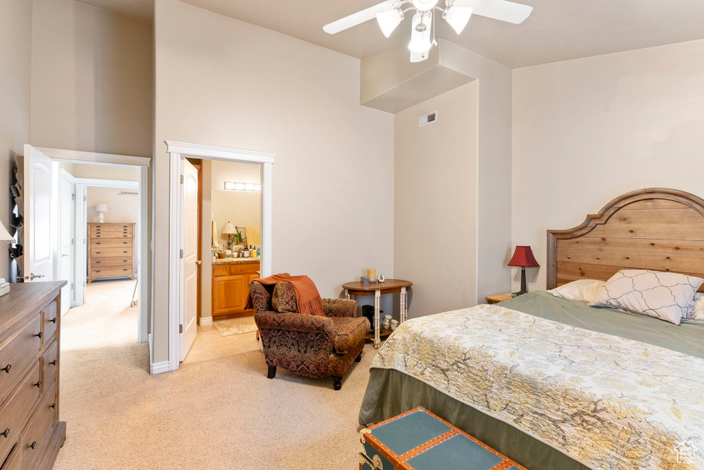 Bedroom with ceiling fan, light colored carpet, and ensuite bathroom