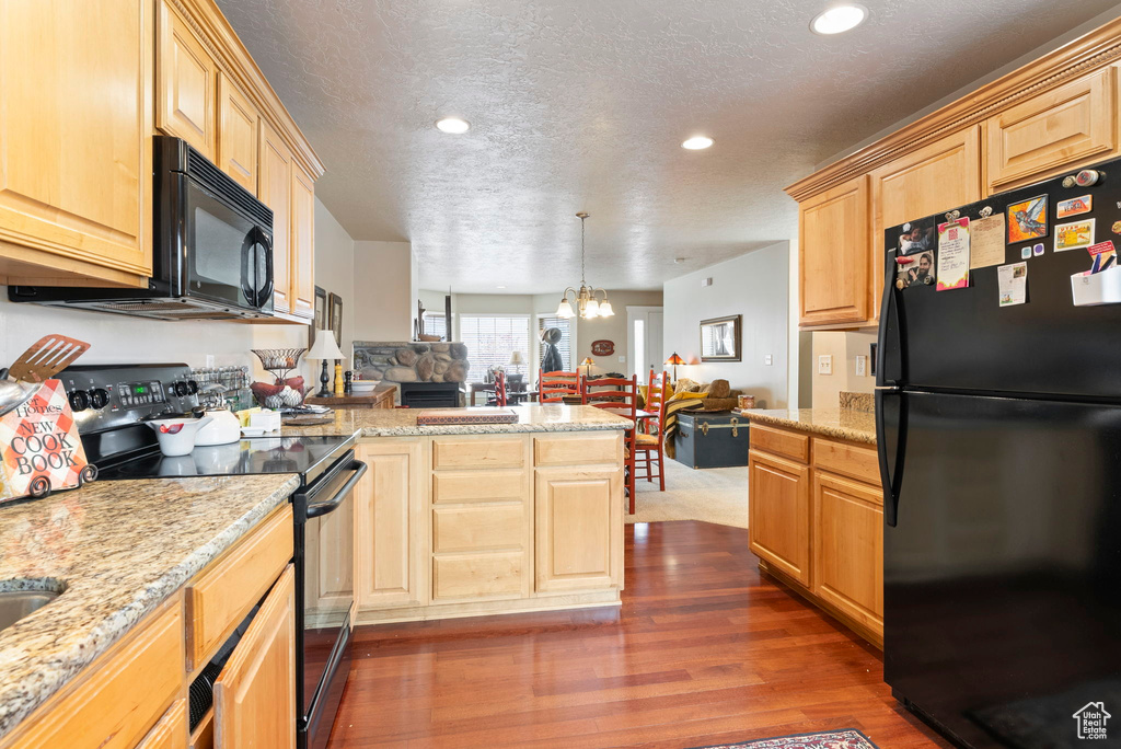 Kitchen with light brown cabinets, black appliances, dark wood-type flooring, a textured ceiling, and a chandelier