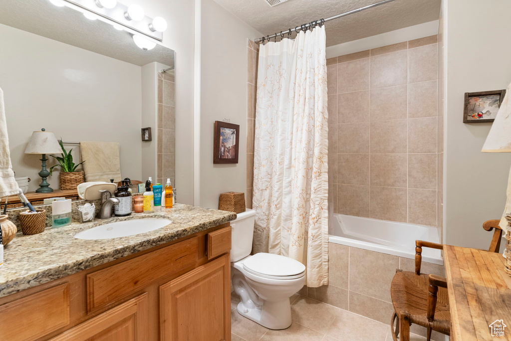 Full bathroom featuring shower / bathtub combination with curtain, tile flooring, a textured ceiling, vanity, and toilet