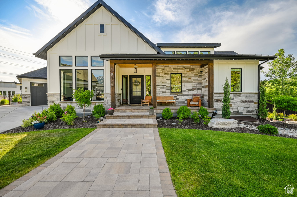 View of front facade with a garage, a front yard, and a porch