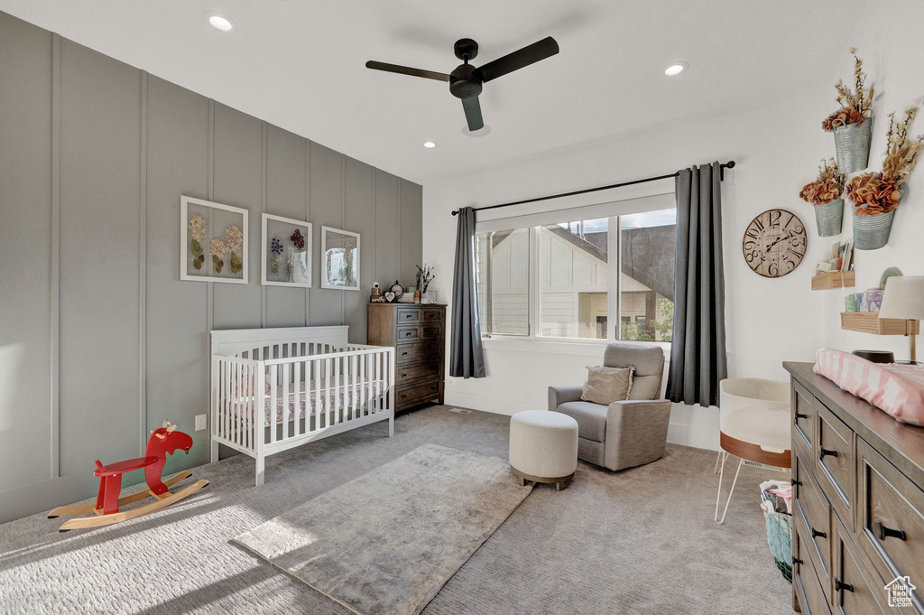 Bedroom with carpet floors, a crib, and ceiling fan