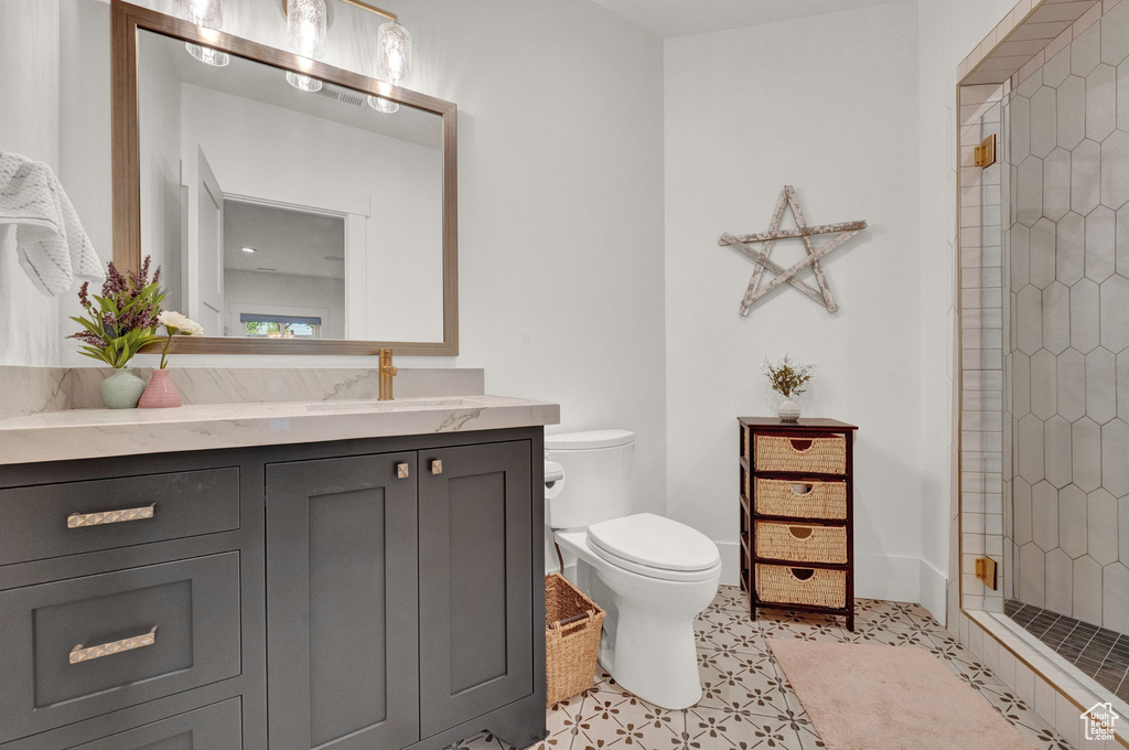 Bathroom with tile floors, tiled shower, oversized vanity, and toilet