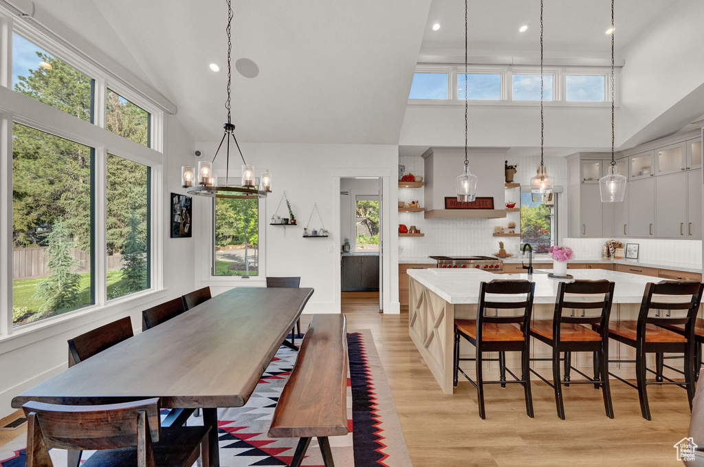 Dining space with high vaulted ceiling, an inviting chandelier, and light hardwood / wood-style floors