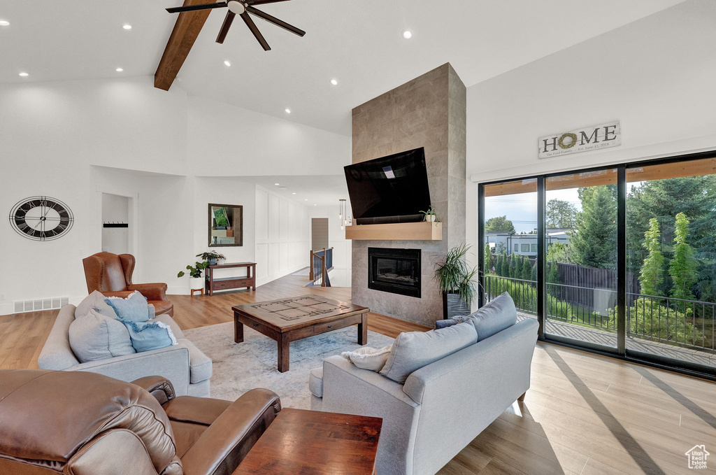 Living room with light wood-type flooring, high vaulted ceiling, a fireplace, and ceiling fan