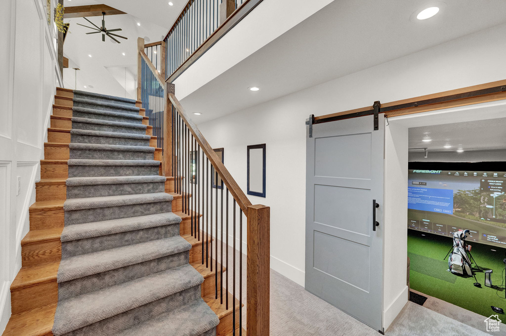 Stairs featuring light colored carpet, a towering ceiling, and a barn door