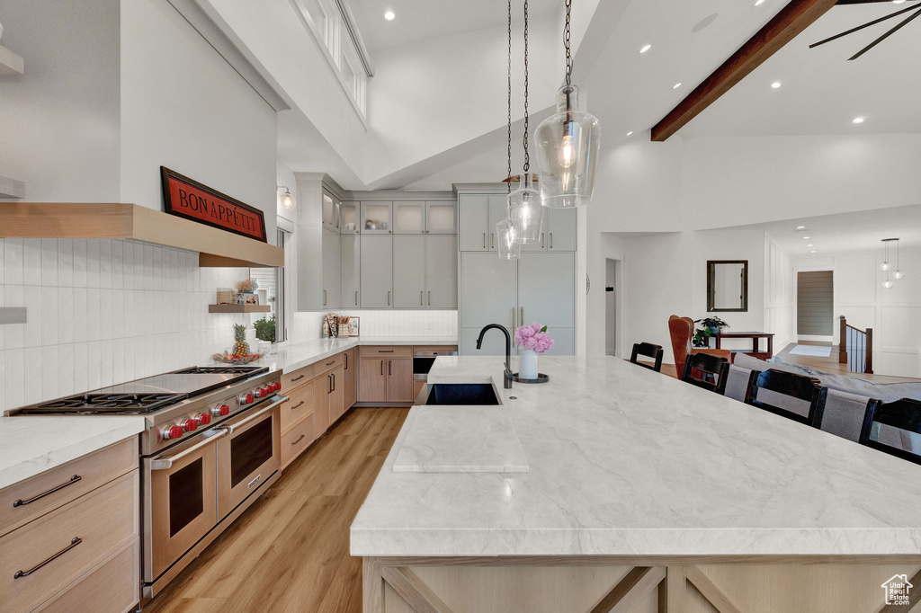 Kitchen with double oven range, high vaulted ceiling, sink, and a kitchen island with sink