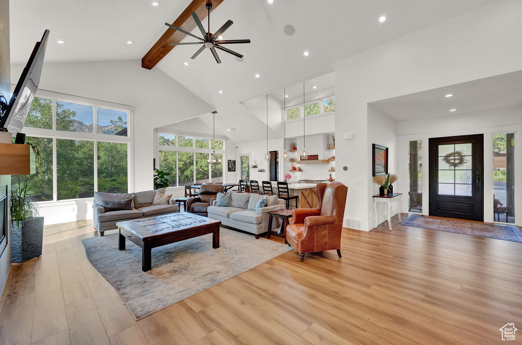 Living room featuring beamed ceiling, high vaulted ceiling, plenty of natural light, and light wood-type flooring