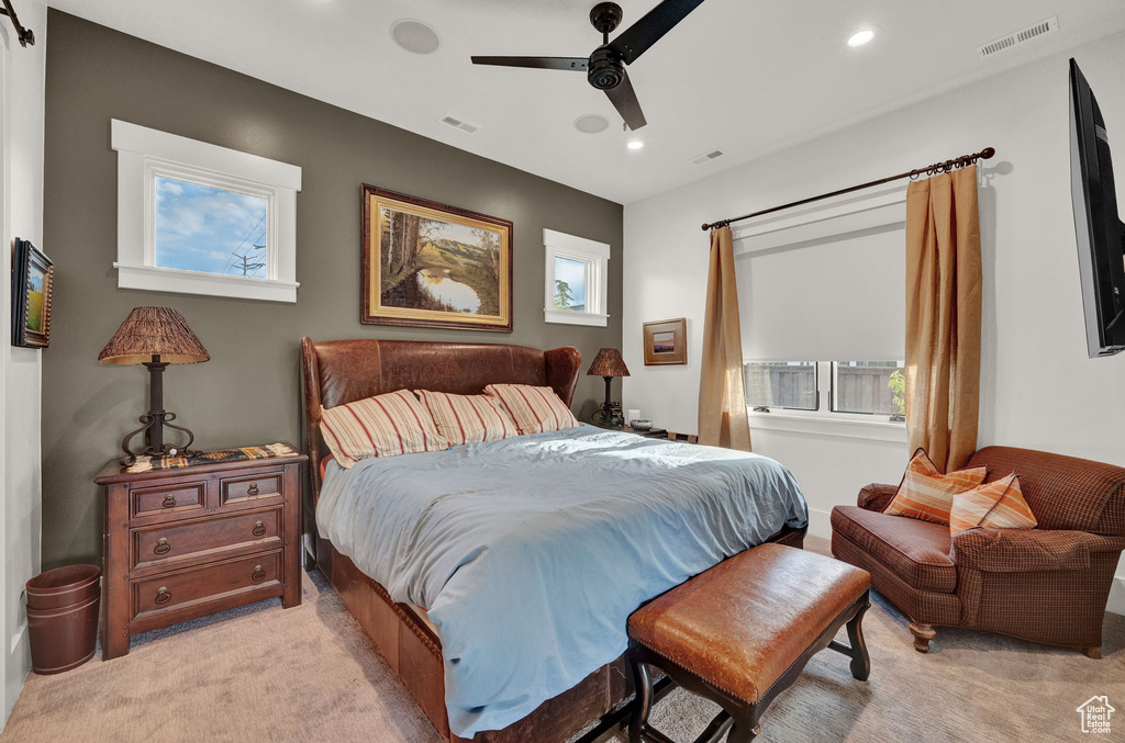 Bedroom with ceiling fan, multiple windows, and light carpet