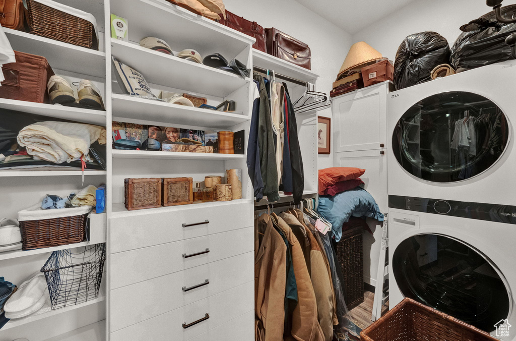 Walk in closet featuring stacked washer and clothes dryer and wood-type flooring