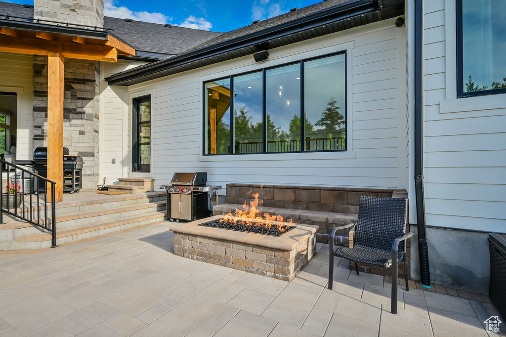 View of terrace with an outdoor fire pit and area for grilling