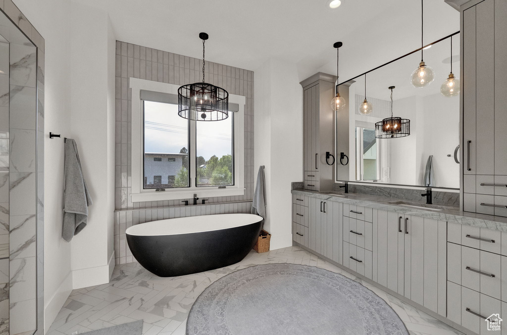 Bathroom with tile walls, tile flooring, vanity, and a tub