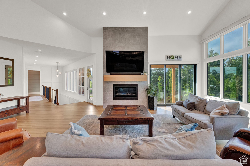 Living room featuring high vaulted ceiling, a tiled fireplace, and wood-type flooring