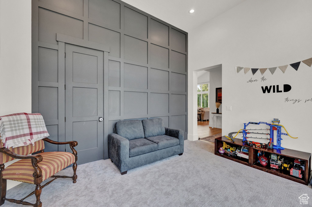 Carpeted living room featuring a towering ceiling