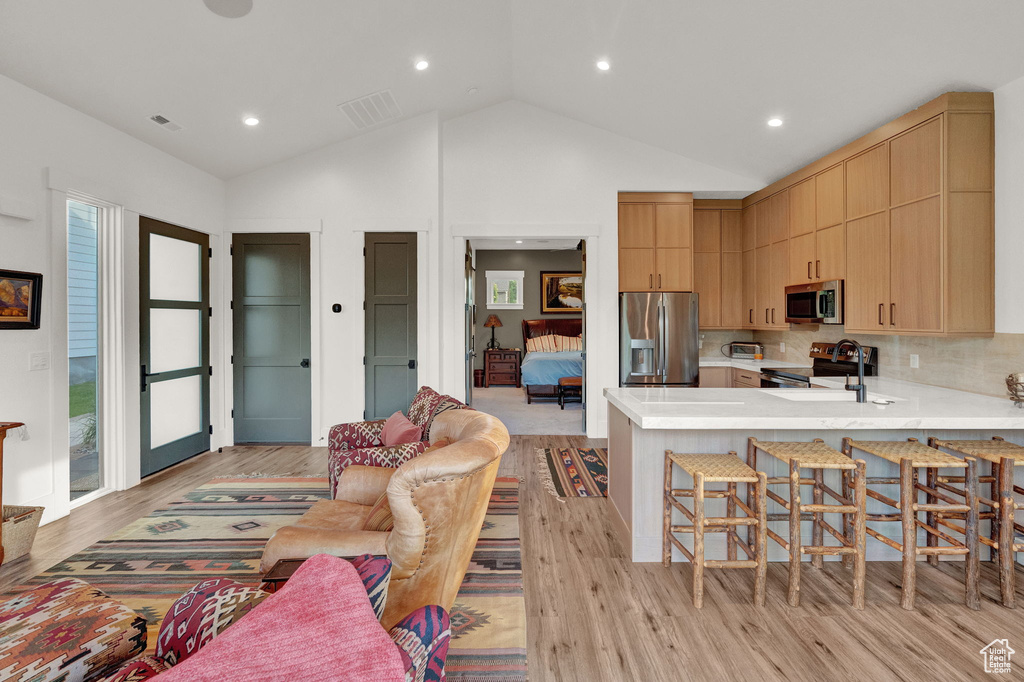 Living room featuring high vaulted ceiling, sink, and light wood-type flooring