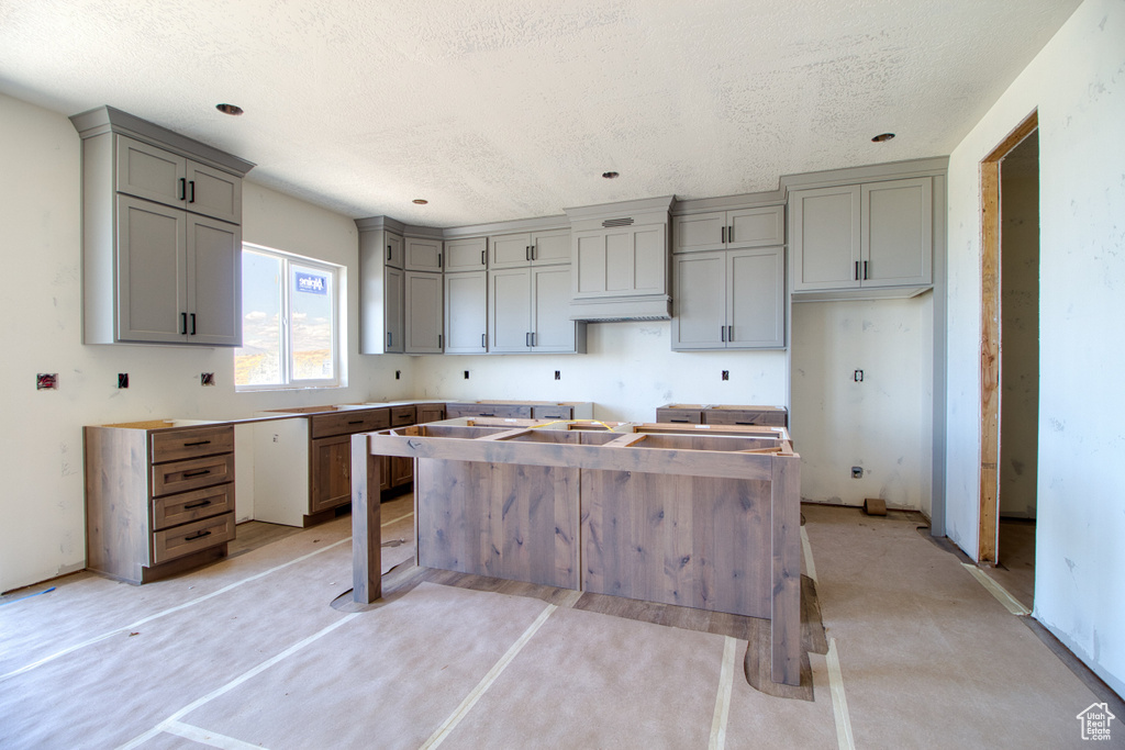 Kitchen featuring a kitchen island, a textured ceiling, and gray cabinetry