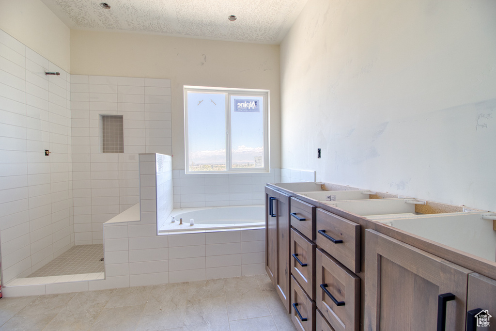 Bathroom with tile patterned flooring, separate shower and tub, vanity, and a textured ceiling