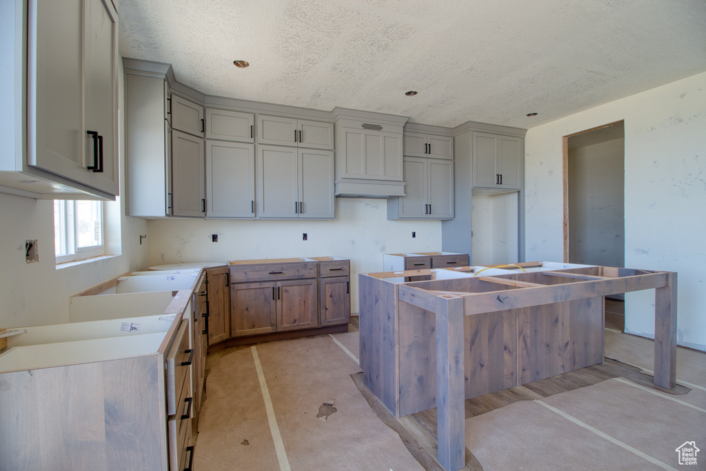 Kitchen featuring a kitchen island, a textured ceiling, and gray cabinets