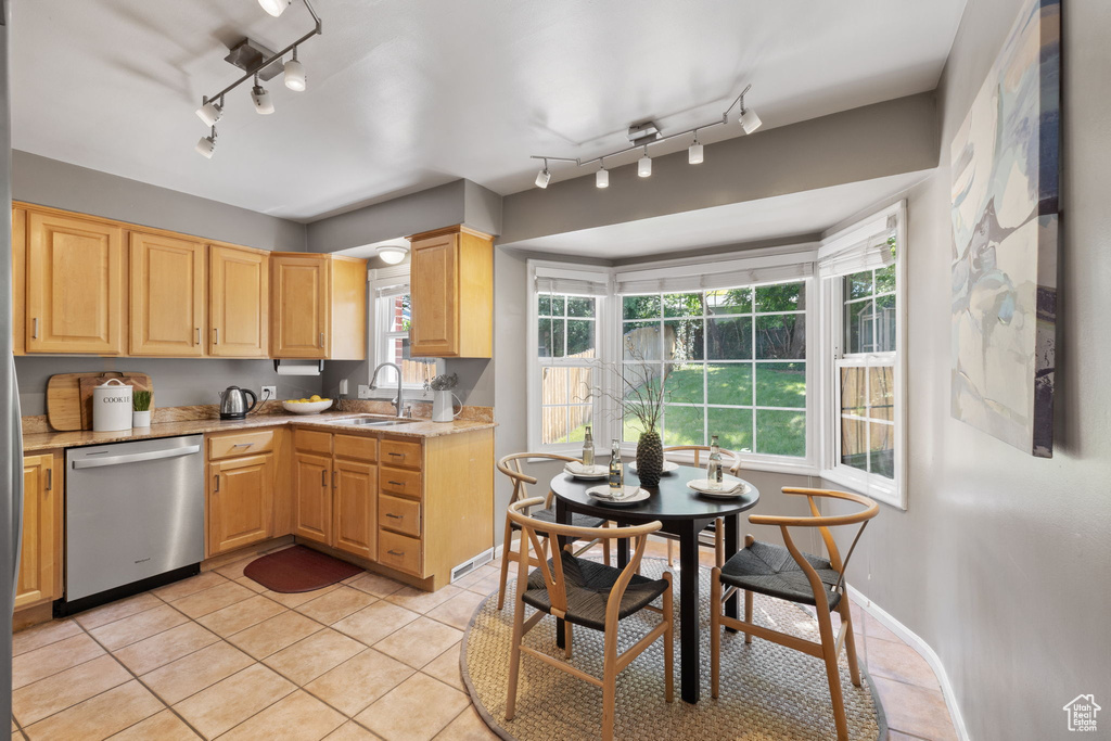 Kitchen with stainless steel dishwasher, rail lighting, sink, light tile floors, and light brown cabinets