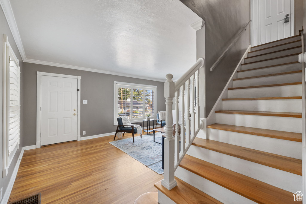 Entrance foyer featuring ornamental molding and light hardwood / wood-style flooring