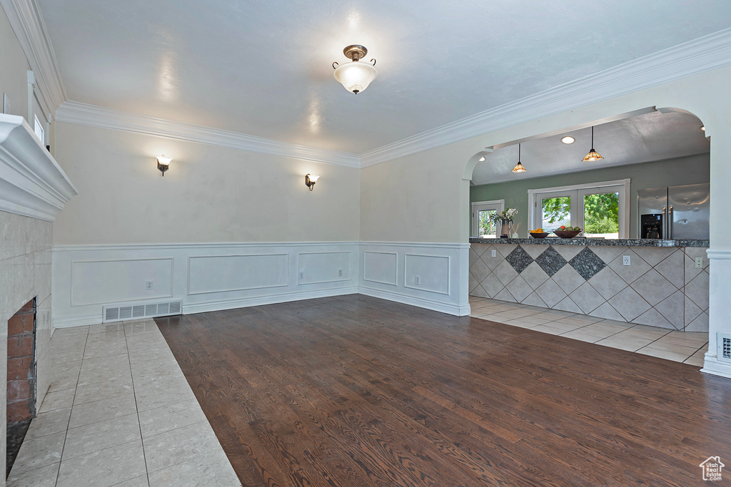 Unfurnished living room featuring crown molding and hardwood / wood-style floors