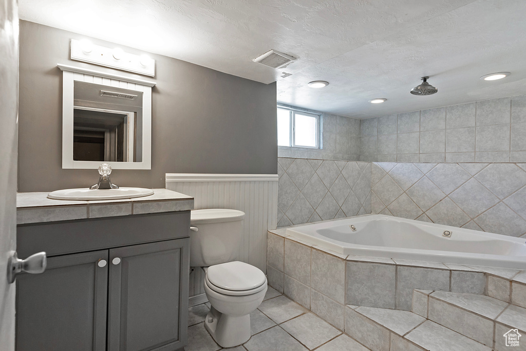 Bathroom with a relaxing tiled bath, vanity, toilet, and tile floors