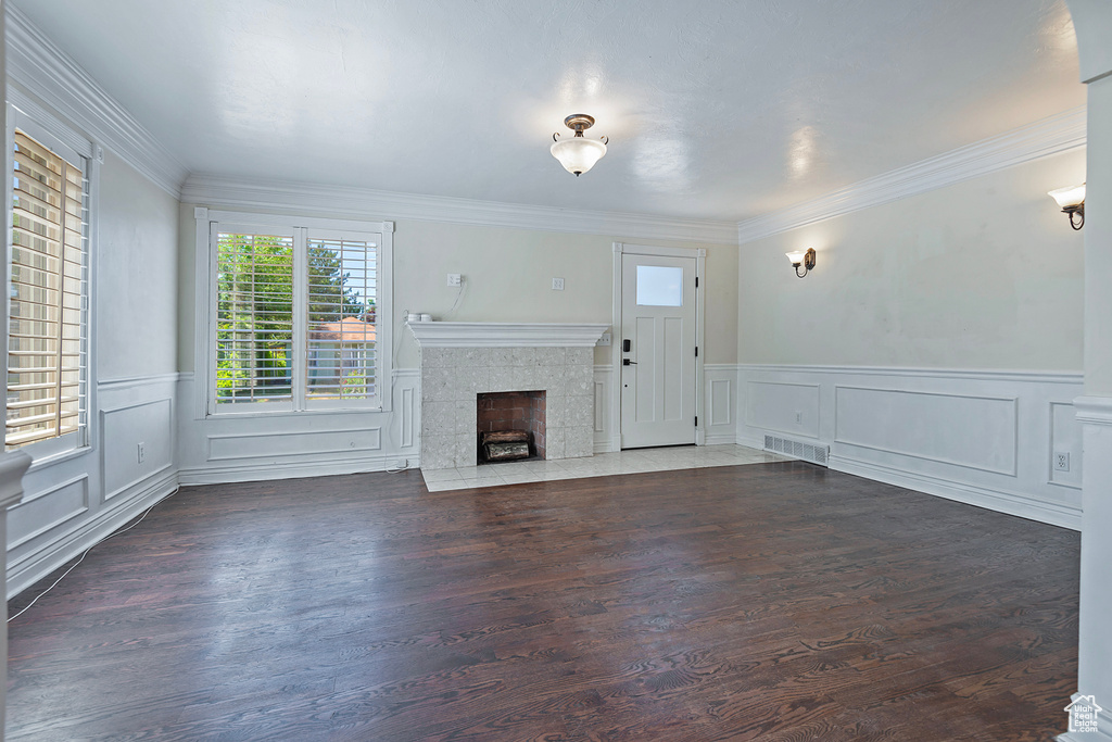 Unfurnished living room featuring crown molding, dark hardwood / wood-style floors, and a tiled fireplace