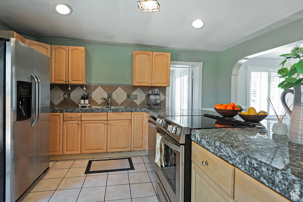 Kitchen with stainless steel appliances, sink, tasteful backsplash, light tile floors, and light brown cabinets