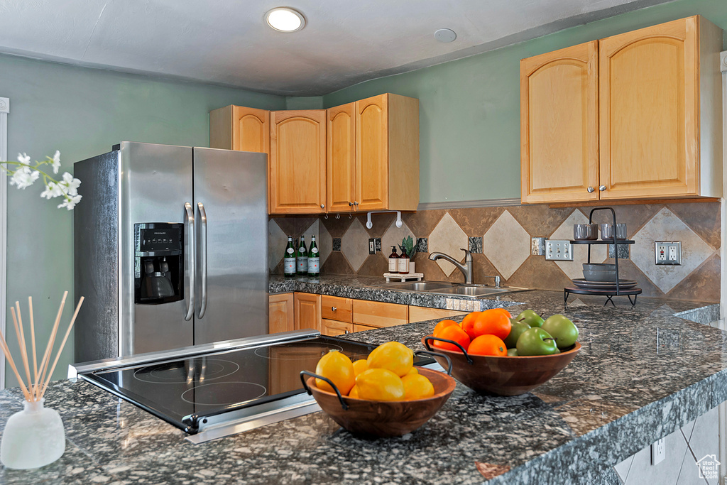 Kitchen with light brown cabinets, sink, stainless steel fridge, and backsplash