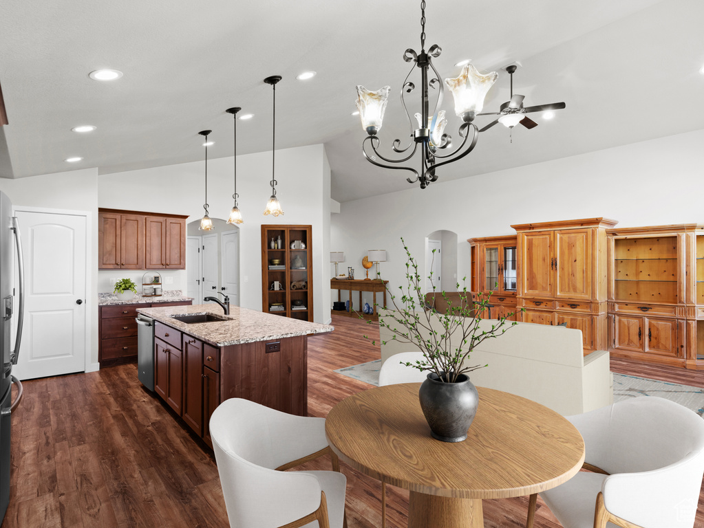 Dining area featuring vaulted ceiling, sink, ceiling fan with notable chandelier, and dark wood-type flooring